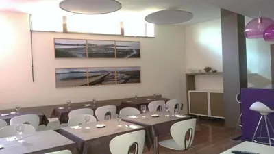 a dining room with tables and white chairs at Isla Nova Hotel in Foz