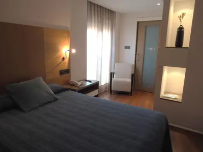 a bedroom with a bed and a room with a chair at Isla Nova Hotel in Foz