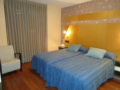 a bedroom with a blue bed and a chair at Isla Nova Hotel in Foz