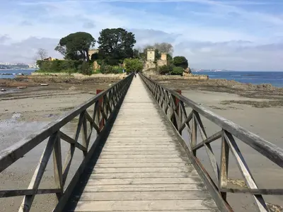 a bridge over a beach with a castle in the background at Villa Dorneda in Oleiros