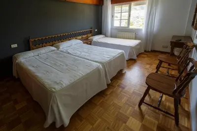 a bedroom with two beds and a chair and a window at As Areas II in Viveiro