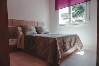 a bedroom with a bed with a blanket and a window at Piso centro in Ourense