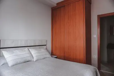a bedroom with a bed and a wooden cabinet at Piso centro in Ourense