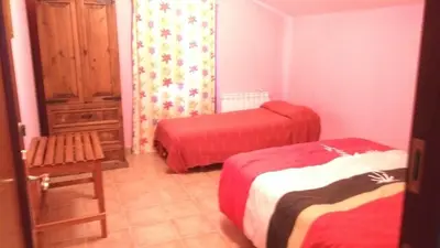 a small room with two beds and a chair at Apartamentos La Panerona in Tineo