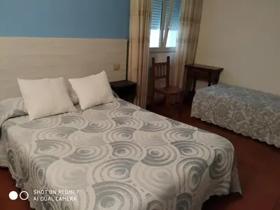 a hotel room with a bed and a bed and a window at Hostal Fisterra in Lugo