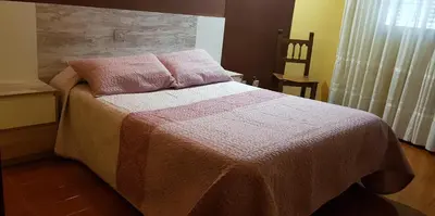 a bedroom with a bed with a pink blanket and a window at Hostal Fisterra in Lugo