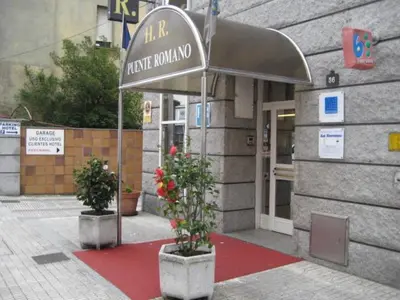 a building with two potted plants in front of a building at Puente Romano in Ourense