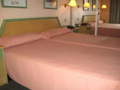 a bedroom with a large bed with pink sheets at Puente Romano in Ourense