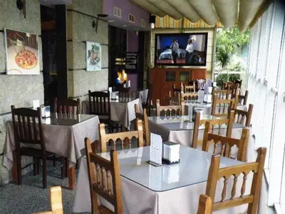 a restaurant with tables and chairs and a television in it at Puente Romano in Ourense