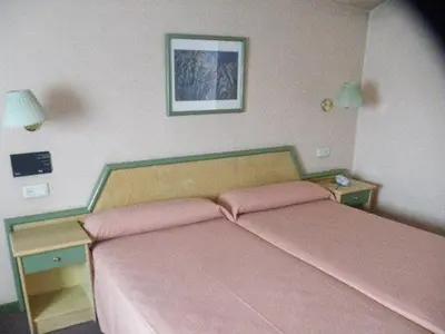 a bedroom with a bed with pink sheets and two tables at Puente Romano in Ourense