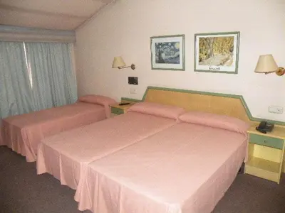 two beds in a hotel room with pink sheets at Puente Romano in Ourense