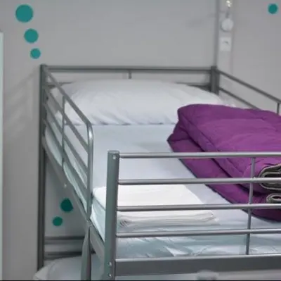 a metal bunk bed with white sheets and purple pillows at Augas Quentes Hostel in Ourense