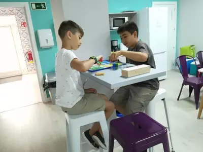 two boys sitting at a table playing with a toy at Augas Quentes Hostel in Ourense