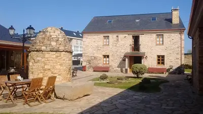 a stone house with a table and chairs in front of it at Alén do Mis - Hotel Rural in Foz