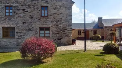 a large stone building with a grass yard at Alén do Mis - Hotel Rural in Foz