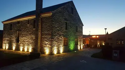 a stone building with lights on the side of it at Alén do Mis - Hotel Rural in Foz
