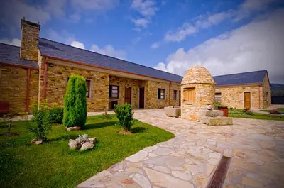 a large stone building with a patio in front of it at Alén do Mis - Hotel Rural in Foz