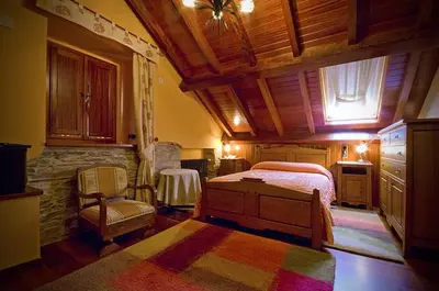 a bedroom with a bed and a chair in a room at Alén do Mis - Hotel Rural in Foz