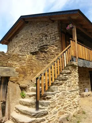 a stone house with a wooden stairway in front of it at CASA RURAL Calma del Lago in Triufé