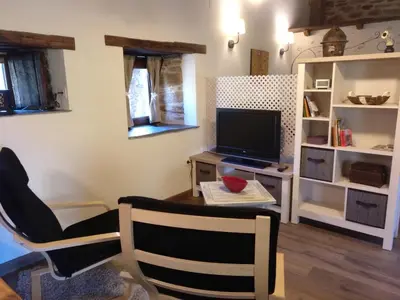a living room with a tv and a table and chairs at CASA RURAL Calma del Lago in Triufé