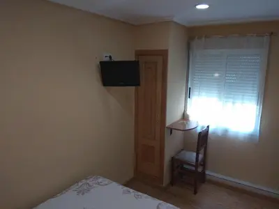 a bedroom with a bed and a chair and a window at Hostal Lido in Ourense