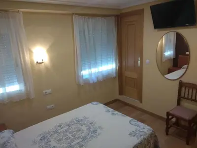 a bedroom with a bed and a mirror and a chair at Hostal Lido in Ourense