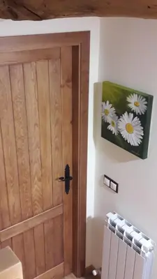 a door in a room with a painting of daisies at Casa Blanquita in Molinaseca