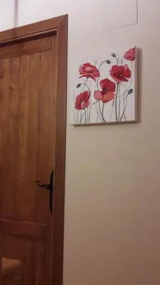 a picture of red flowers on a wall next to a door at Casa Blanquita in Molinaseca