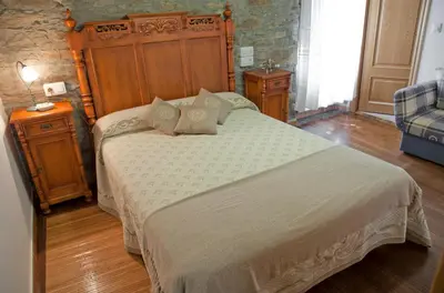 a bedroom with a large bed with a wooden headboard at Costa da Egoa in Carral