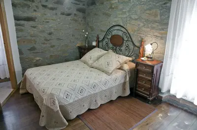 a bedroom with a bed and a table with a lamp at Costa da Egoa in Carral