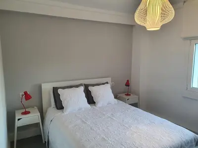a white bedroom with a large bed with two tables at AdA Apartamento in Santiago de Compostela