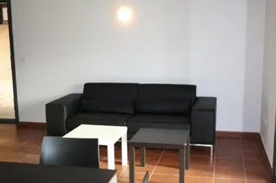 a living room with a black couch and a table at Alojamiento Ubaldo Nieto in Carracedo del Monasterio