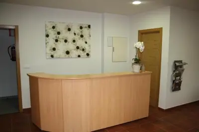 a lobby with a counter with a flower painting on the wall at Alojamiento Ubaldo Nieto in Carracedo del Monasterio