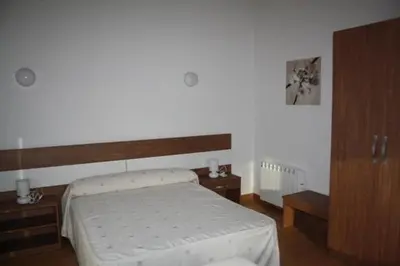 a bedroom with a bed and a wooden cabinet at Alojamiento Ubaldo Nieto in Carracedo del Monasterio