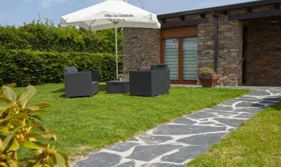 a patio with two chairs and an umbrella at Villas Las Catedrales in Ribadeo