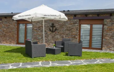a group of chairs under an umbrella in a yard at Villas Las Catedrales in Ribadeo