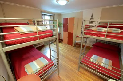 a room with three bunk beds with red sheets at Albergue O Fogar de Teodomiro in Santiago de Compostela