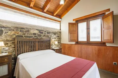 a bedroom with a bed and a stone wall at Casa Rural Dona María in Ordes