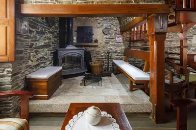 a living room with a fireplace and a stone wall at Casa Rural Dona María in Ordes