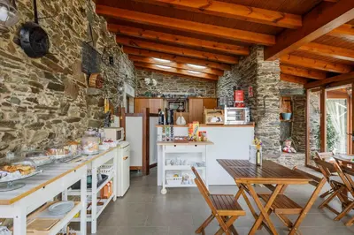 a kitchen with a table and a stone wall at Casa Rural Dona María in Ordes