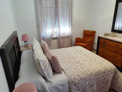 a bedroom with a bed with pillows and a chair at CASA DE CAMPO TRANQUILA EN VILAR CERCA DE SANTIAGO in Touro