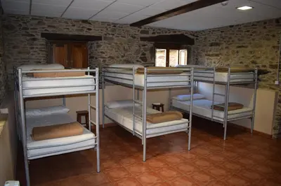a room with four bunk beds in a room with a window at Pensión Albergue Los Caminantes in Ribadiso