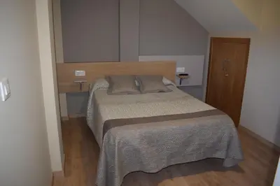 a small bedroom with a bed and a wooden door at Pensión Albergue Los Caminantes in Ribadiso