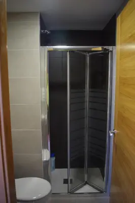 a shower stall with a toilet in a bathroom at Pensión Albergue Los Caminantes in Ribadiso