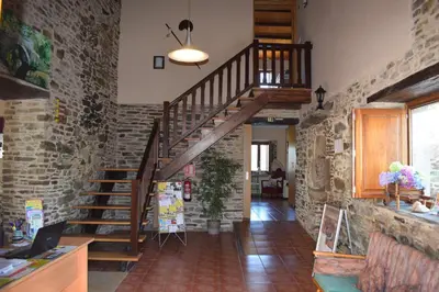 a wooden staircase in a room with a brick wall at Pensión Albergue Los Caminantes in Ribadiso