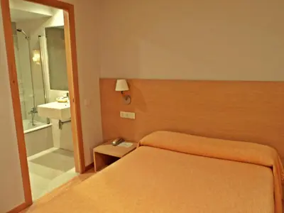 a bedroom with a bed and a bathroom with a sink at Hotel Windsor in Santiago de Compostela