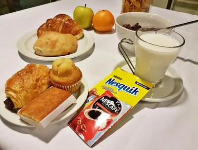 a table with plates of pastries and a glass of milk at Hotel Windsor in Santiago de Compostela