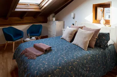 a bedroom with a bed and two blue chairs at Hostal Pension Artilleiro in Santiago de Compostela