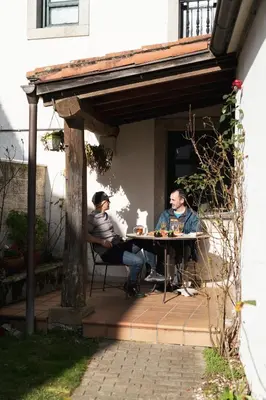 two men are sitting at a table under an outdoor table at Hostal Pension Artilleiro in Santiago de Compostela