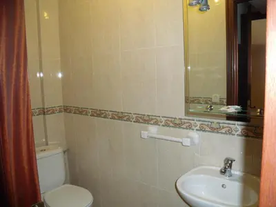 a bathroom with a toilet and a sink and a mirror at Hostal O Patron in Santiago de Compostela